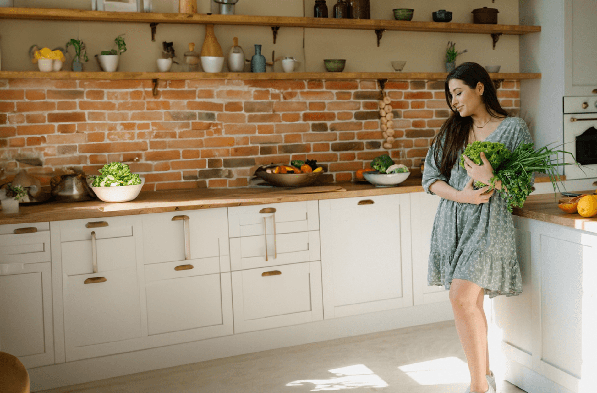 Tatiana standing in a bright kitchen holding fresh leafy greens